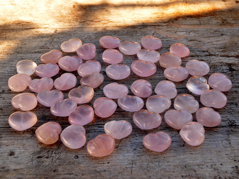 Several rose quartz puffy heart crystals 30mm on wood table