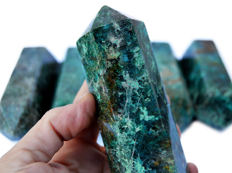 Some large green chrysocolla tower point 110mm on hand with background with some crystals