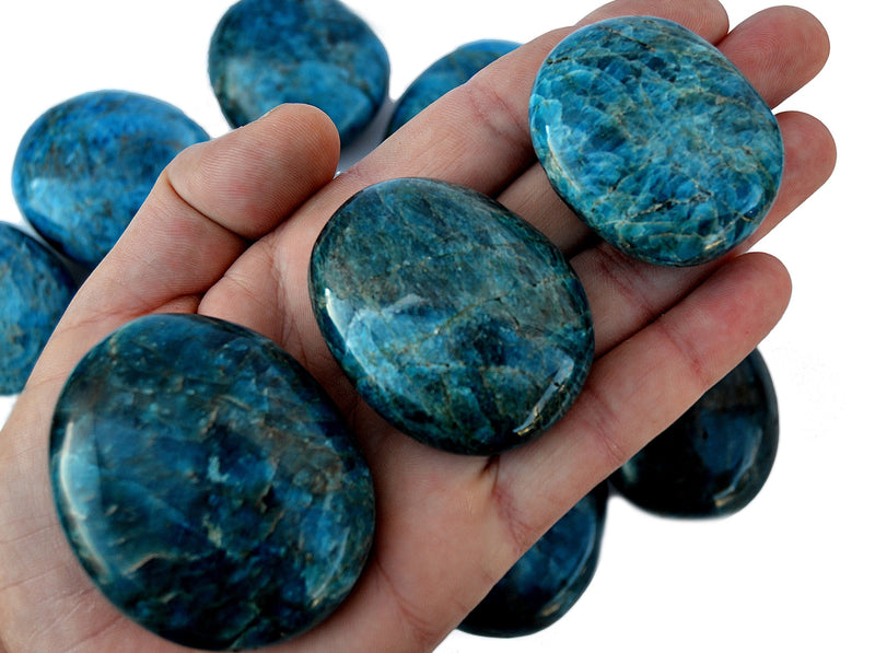 Three large blue apatite palm stones 70mm-40mm on hand with background with some crystals