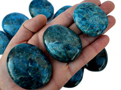 Three large blue apatite palm stones 70mm-40mm on hand with background with some crystals