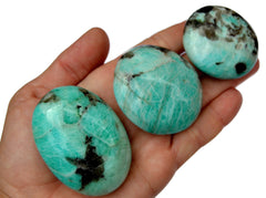 Three green amazonite palm stones 60mm-40mm on hand with white background