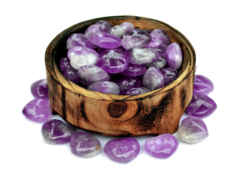 Several small amethyst crystal heart stones 30mm inside a bowl with some hearts forming a circle around