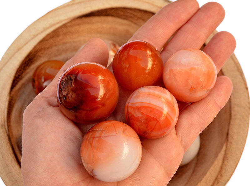 Several orange and red carnelian crystal spheres 25mm - 35mm on hand 