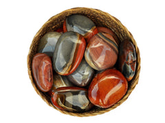 Several polychrome jasper palm stones 40mm-70mm inside a basket on white background