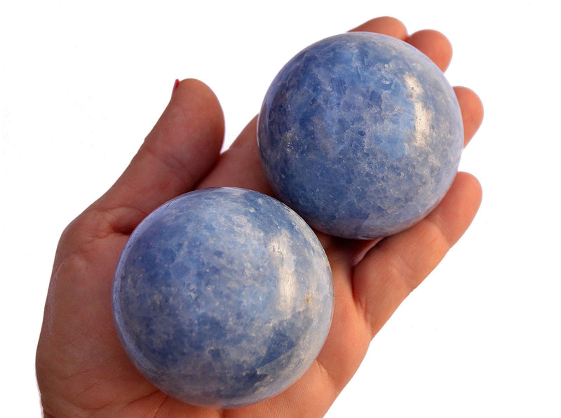 Two blue calcite mineral spheres 60mm on hand