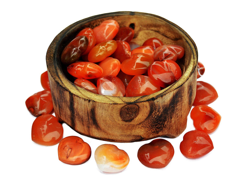 Several small carnelian crystal hearts 30mm inside a bowl with some stones otuside forming a circle around