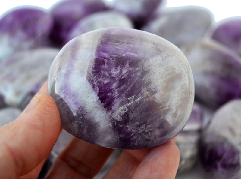 One amethyst palm stone crystal 55mm on hand with background with several crystals