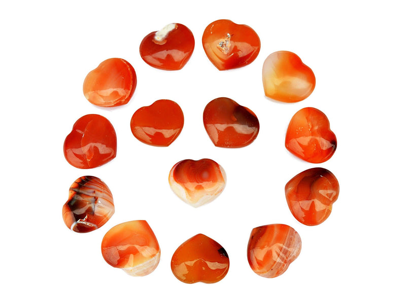 Several natural carnelian crystal hearts 30mm forming a circle on white background