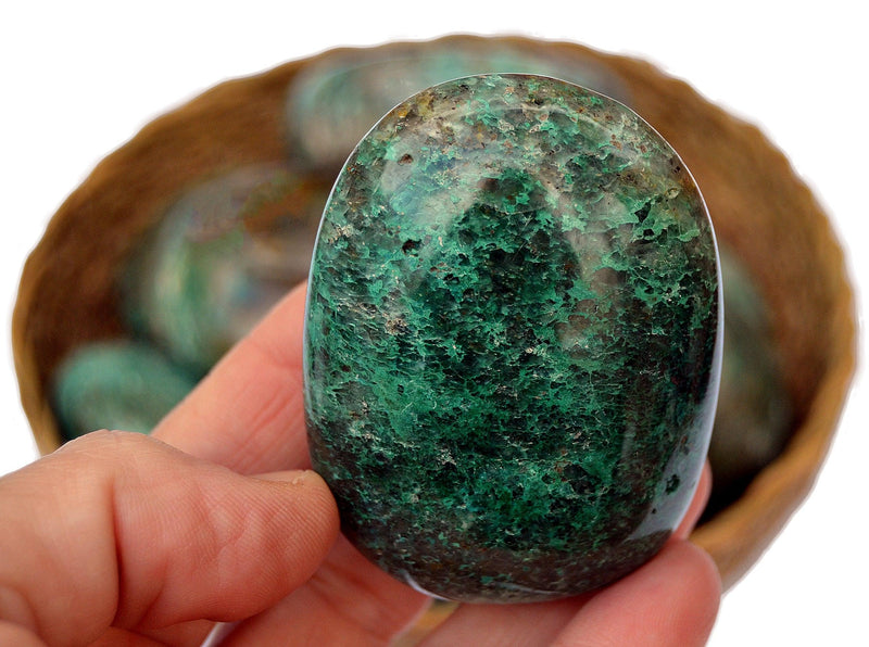 Large green chrysocolla 60mm on hand with background with some crystals inside a basket