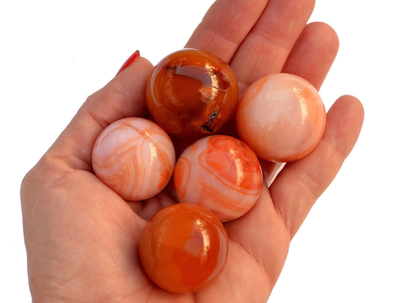 Several orange and red carnelian crystal spheres 30mm - 35mm on hand