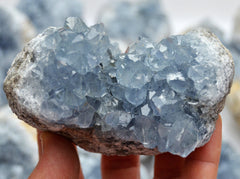 Chunky blue celestite druzy crystal 70mm on hand with background with some stones