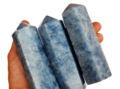 Three blue calcite crystal towers 110mm on hand with white background