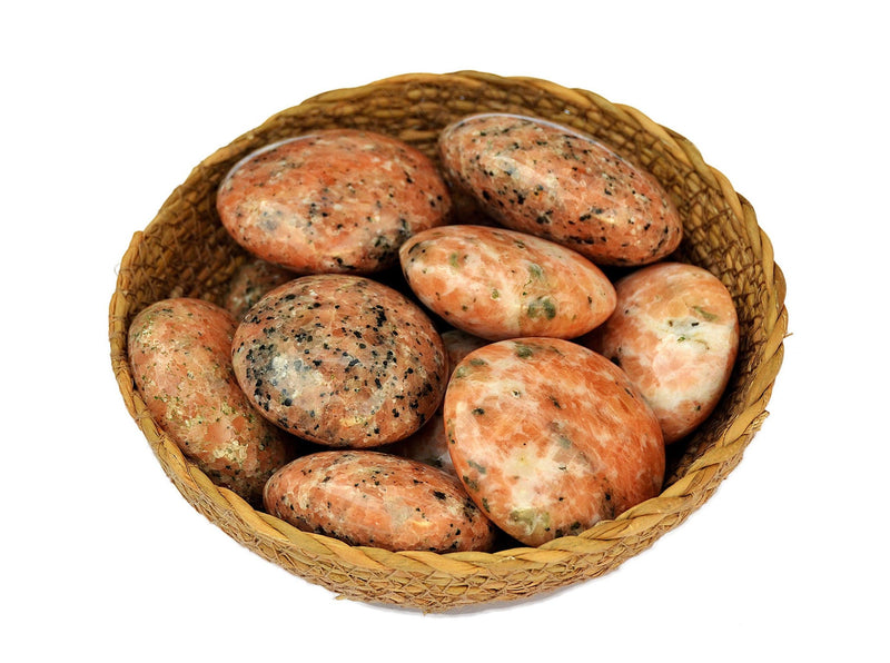 Several orange calcite palm stones 40mm-65mm inside a basket on white background