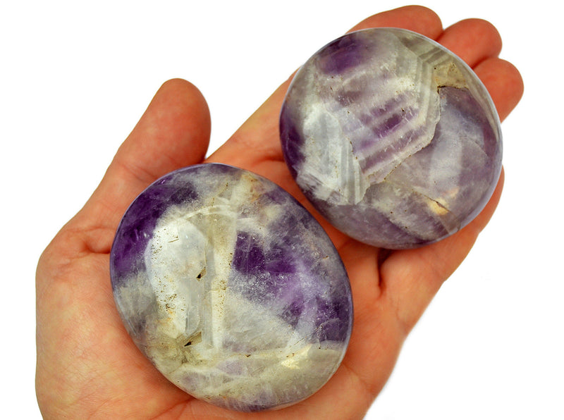 Two amethyst crystal palm stones 50mm - 60mm on hand with white background