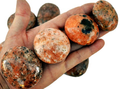 Four orange calcite palm stones on hand