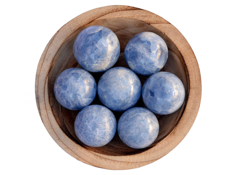 Several blue calcite crystal balls 40mm-60mm inside a wood bowl on white background