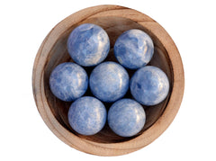 Several blue calcite crystal balls 40mm-60mm inside a wood bowl on white background