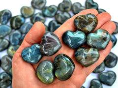 Some labradorite heart crystals 30mm on hand with background with several hearts on white background
