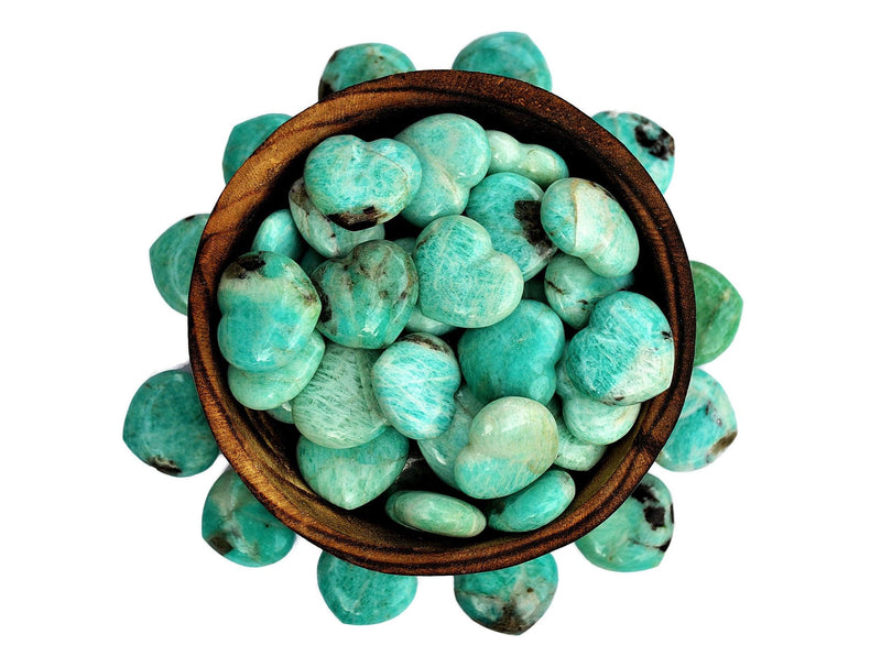 Several amazonite stone hearts 30mm inside a bowl with some crystals around on white background