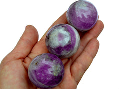 Three amethyst crystal spheres 45mm on hand with white background