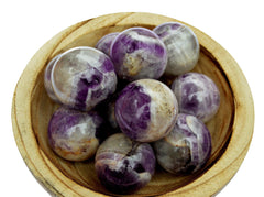 Several amethyst crystal spheres 45mm-60mm inside a wood bowl