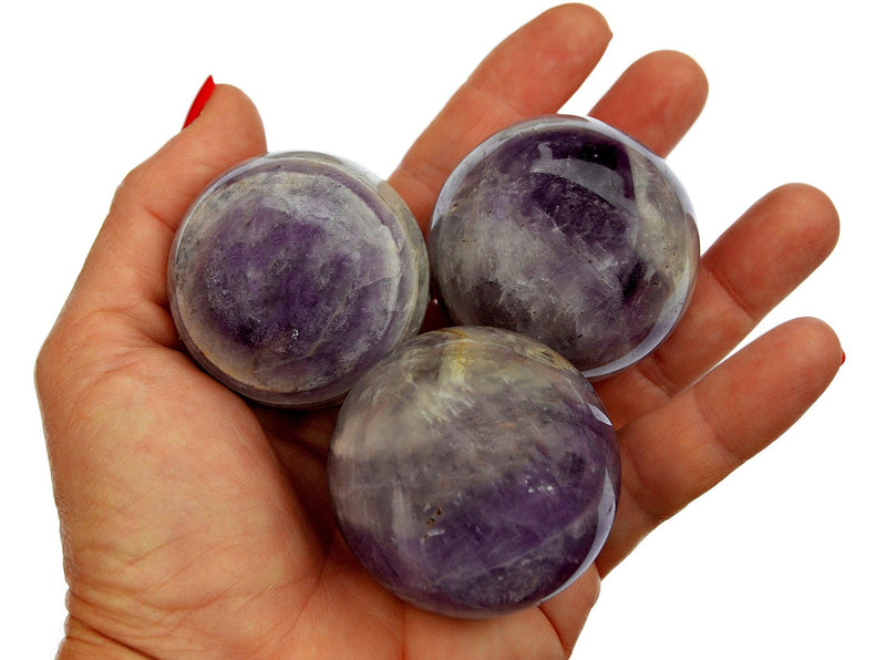 Trhee amethyst sphere stones 55mm-60mm on hand with white background