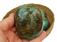 Big chrysocolla 60mm on hand with background with some crystals inside a basket