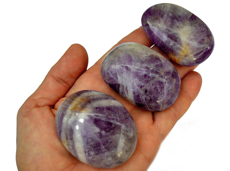 Three purple amethyst crystal palm stones 40mm - 60mm on hand with white background