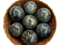 Some blue labradorite crystal spheres inside a basket on white background