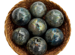 Some labradorite crystal spheres inside a basket on white background