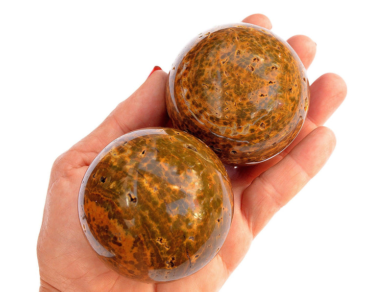 Two ocean jasper sphere crystal stones 55mm on hand with white background