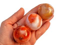 Three carnelian crystal spheres 35mm-40mm on hand with white background