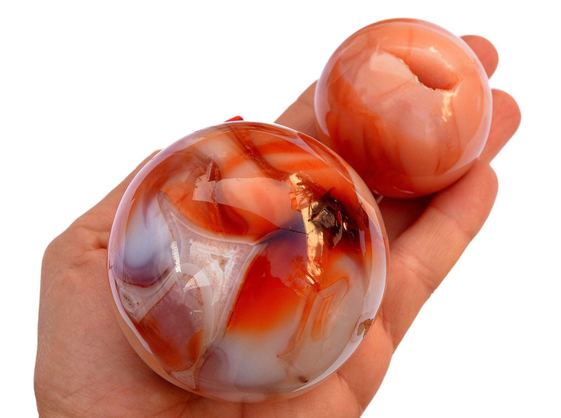 Two natural carnelian mineral spheres 45mm-65mm on hand with white background