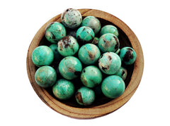 Several green amazonite crystal balls 25mm - 40mm inside a wood bowl and white background