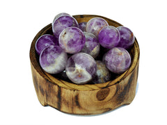 Several small amethyst crystal balls 25mm - 40mm inside a bowl on white background