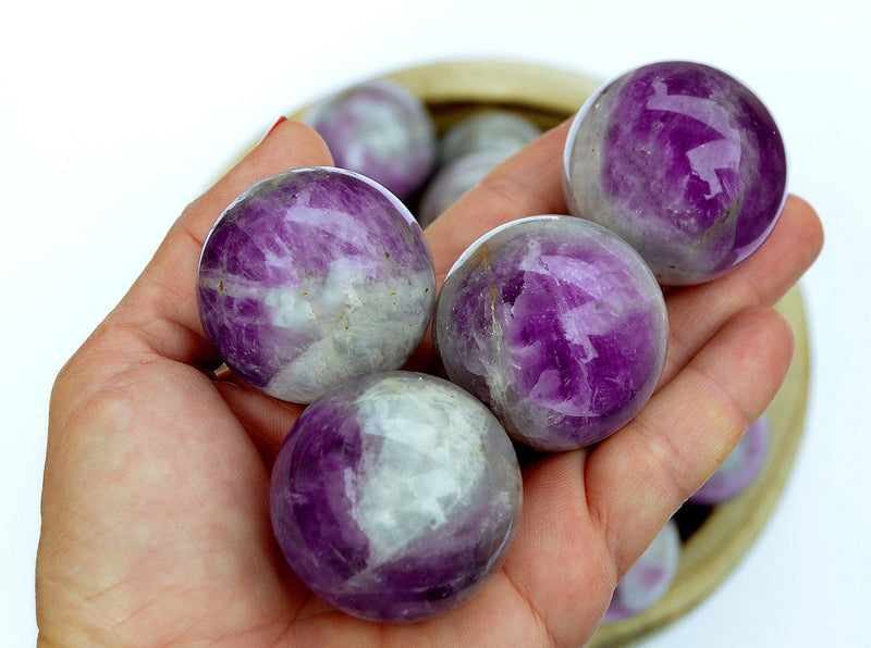 Some amethyst sphere stones 45mm - 55mm on hand with white background