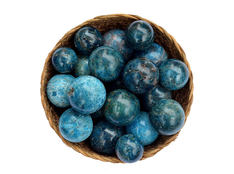 Several blue apatite crystal spheres 25mm-40mm inside a basket on white background