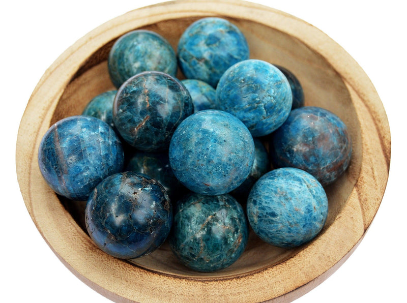 Several blue apatite crystal balls 45mm-60mm inside a wood bowl on white background