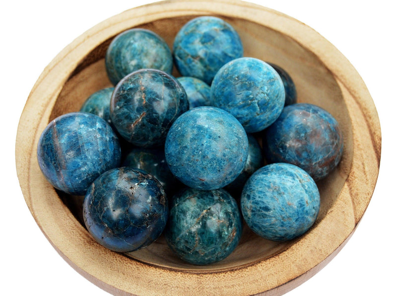 Several blue apatite crystal balls 45mm-60mm inside a wood bowl on white background