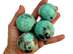 Four amazonite sphere crystals 45mm-55mm on hand with white background