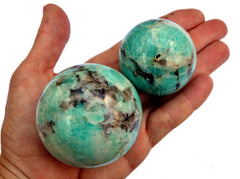 Two amazonite sphere crystals 45mm-60mm on hand with white background