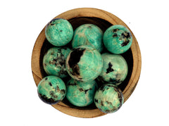 Some green amazonite crystal spheres 45mm-60mm inside a wood bowl on white background