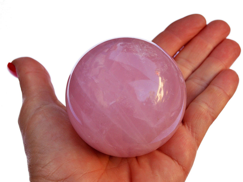 Large rose quartz sphere stone 60mm on hand with white background