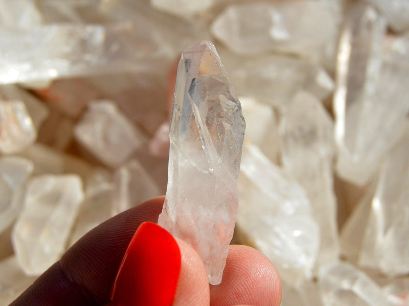 One small raw crystal point on hand with background with several points