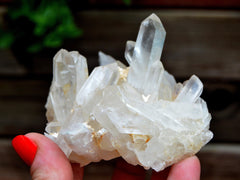 One rough quartz cluster on hand with wood background