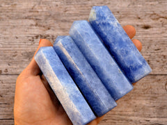 Four blue calcite crystal towers 90mm on hand with wood background
