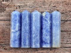 Five blue calcite faceted point crystals on wood table