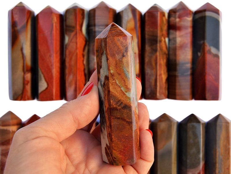 One desert jasper crystal obelisk 90mm on hand with background with some points on white