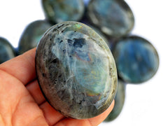 Large labradorite palm stone 75mm on hand with background with some crystals