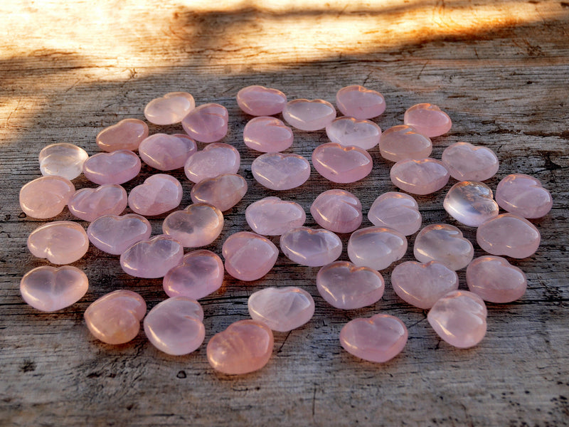 Several small pink quartz crystal hearts 30mm on wood table